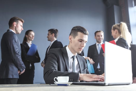 Business man working with laptop, team of coworkers on background