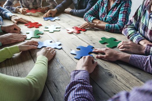Business people and puzzle on wooden table, teamwork concept