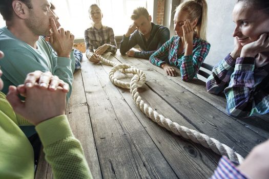 Problem solution concept, team of people in casual clothes sitting around the table with rope node