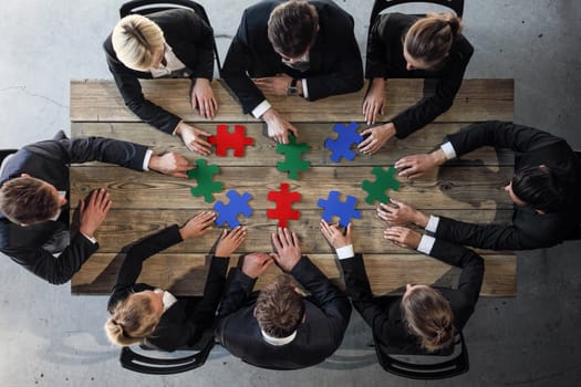 Business people and puzzle on wooden table, teamwork concept