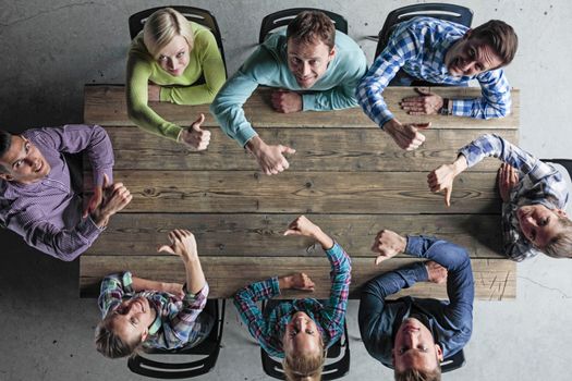 Modern business meeting concept, people in casual clothes sitting around wooden table with thumbs up