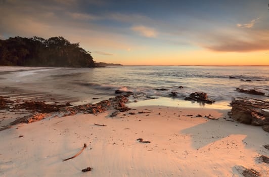 Morning sun casts golden light and long shadows onto the beach.