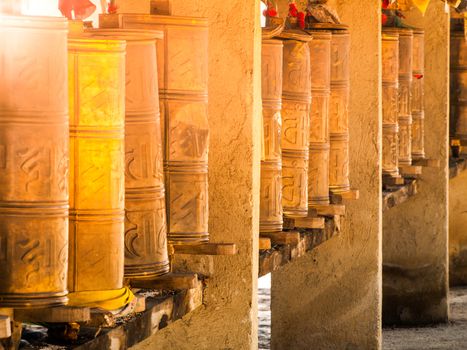 Row of metal prayer wheels. Traditional Tibetan Buddhist object.