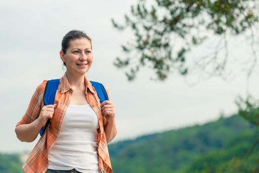 horizontal portrait of a beautiful brunette with a backpack on nature in a hike