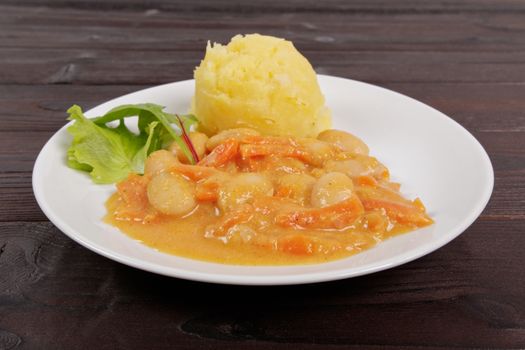 Beans with carrots and potatoes on a wooden table