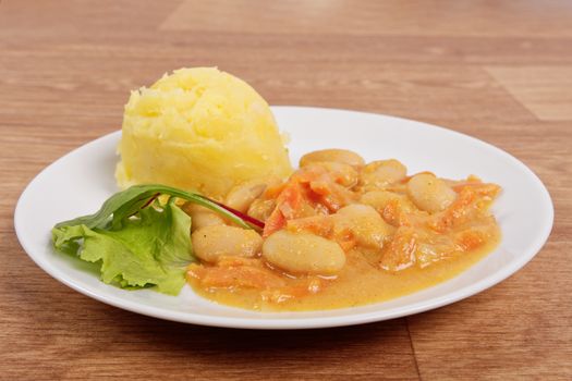 Beans with carrots and potatoes on a wooden table