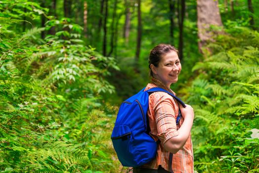 happy woman with a backpack strolling through the park