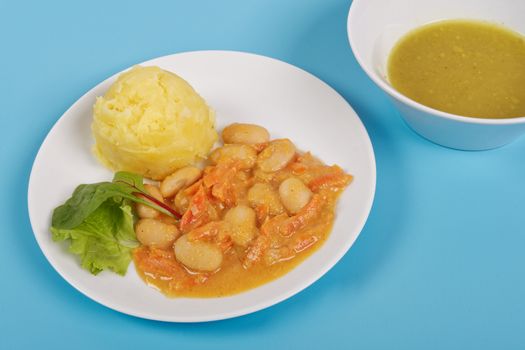 Beans with carrots and potatoes on a blue background