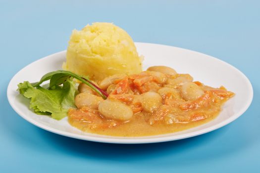 Beans with carrots and potatoes on a blue background