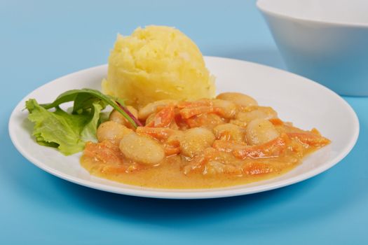 Beans with carrots and potatoes on a blue background