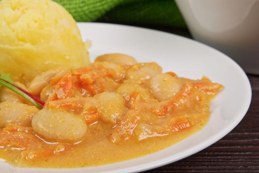 Beans with carrots and potatoes on a wooden table