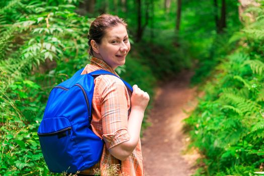 portrait of a brunette with a backpack in a green forest in a hike