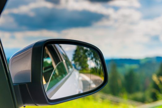 car mirror with reflection of a beautiful landscape in it, close-up