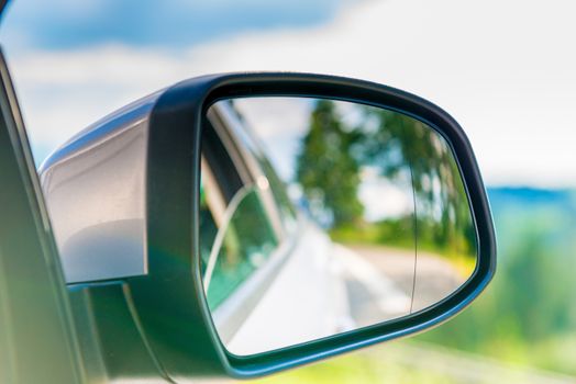 car side mirror with a reflection of the beautiful scenery in it, close-up