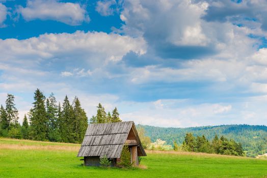 old wooden hut in the field against the backdrop of a beautiful landscape