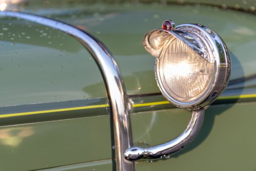 Headlamp and chrome decoration detail on hood of vintage classic oldtimer car