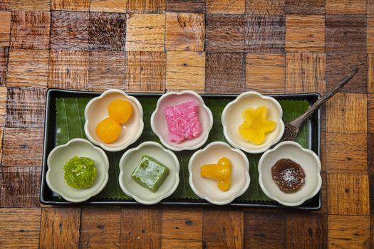 New year varity candy ,Colorful of Thai steamed layer cake in cube and fried pastry Golden Ball,Deep-fried candy drop and Jackfruit in old style of black plate.