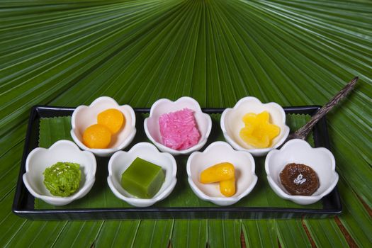 New year varity candy ,Colorful of Thai steamed layer cake in cube and fried pastry Golden Ball,Deep-fried candy drop and Jackfruit in old style of black plate.