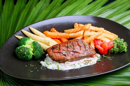 Duck steak on black plate with potatoes and baby corn ,celery 