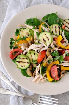 Warm chicken salad with spinach, tomato slices, sweet pepper, grilled zucchini, and champignons, all dressed with herbs and fragrant oil.