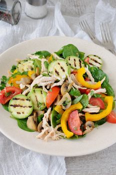 Warm chicken salad with spinach, tomato slices, sweet pepper, grilled zucchini, and champignons, all dressed with herbs and fragrant oil.
