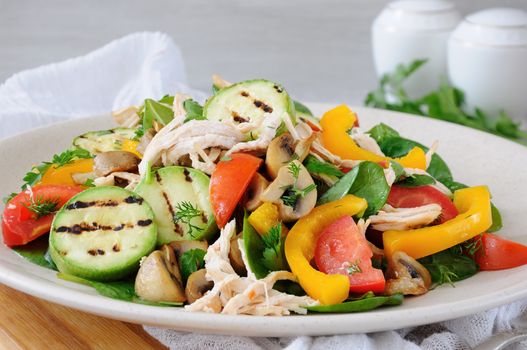 Warm chicken salad with spinach, tomato slices, sweet pepper, grilled zucchini, and champignons, all dressed with herbs and fragrant oil.