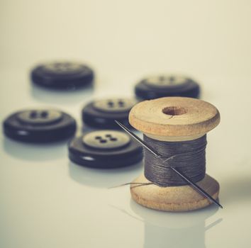 spool of thread and buttons on white background