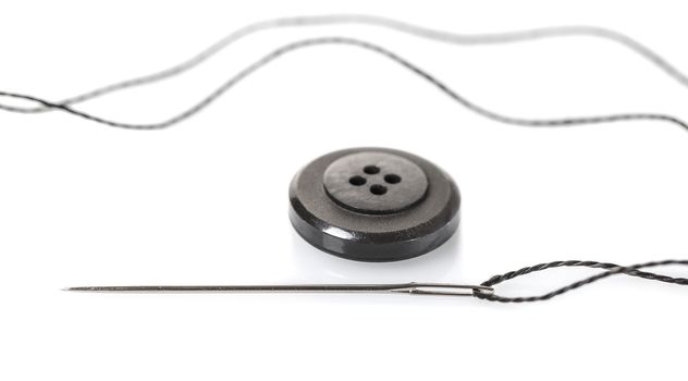 needle with thread and button on white isolated background