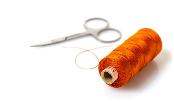 spool of thread and scissors on white isolated background