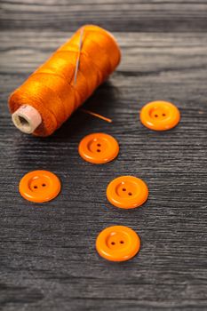 spool of threads and buttons on a wooden background