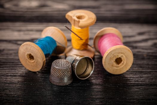 Thread and thimble on a black wooden background