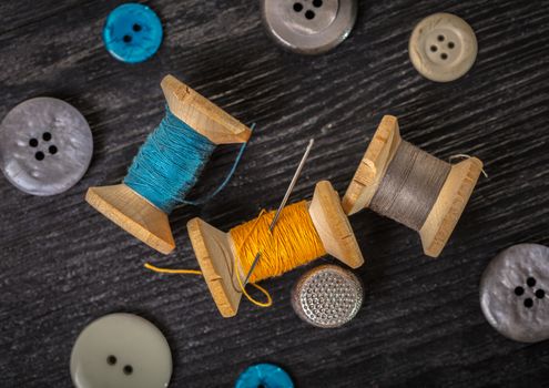 spool of threads and buttons on a wooden background