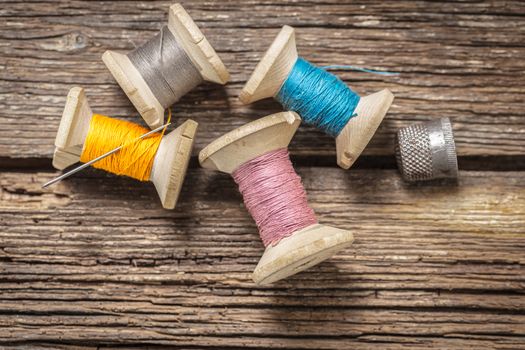 colored threads and thimble on wooden background