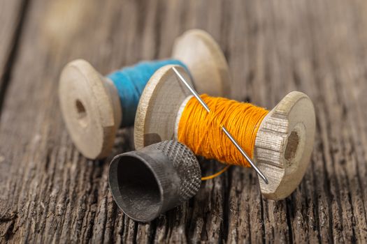 colored threads and thimble on wooden background