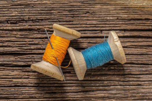 colored threads and needle on wooden background