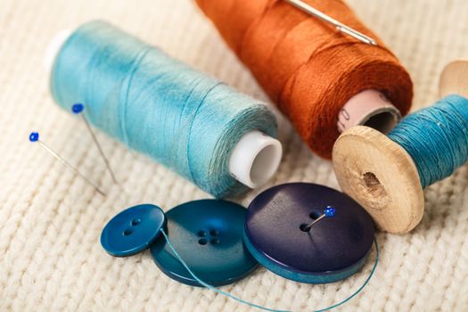 colored thread and buttons on white knitted fabric