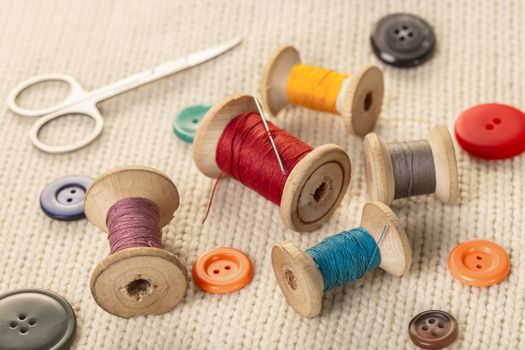 colorful threads and buttons on white knitted fabric