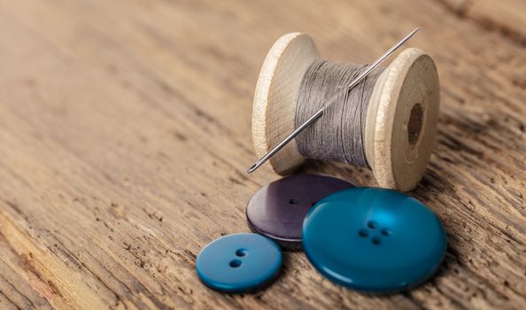 spool of threads and buttons on a wooden background