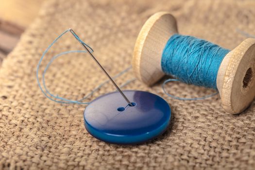 blue button with needle and thread close-up