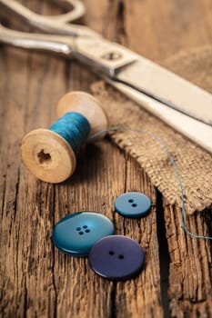 blue thread with buttons and scissors, wooden background