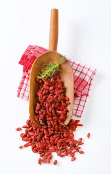 scoop of healthy goji berries and rosemary twigs on checkered dishtowel