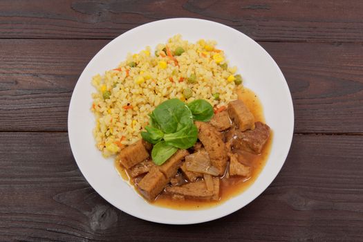 Tempeh with tomato sauce and millets on a wooden table