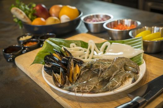 Raw seafood on plate with fruits and vegetables, healthy food, prawn, clam squid.