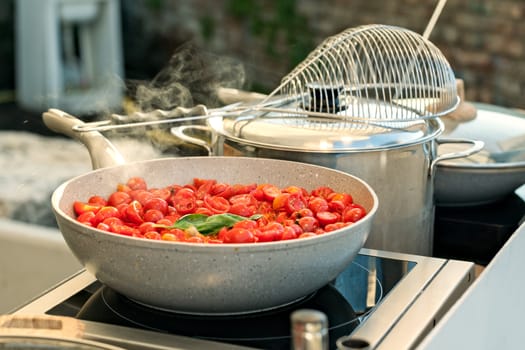 Sliced cherry tomatoes with basil cooking on a saucepan
