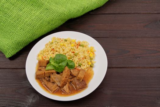 Tempeh with tomato sauce and millets on a wooden table