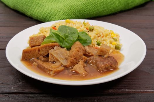 Tempeh with tomato sauce and millets on a wooden table