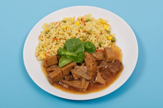 Tempeh with tomato sauce and millets on a blue background