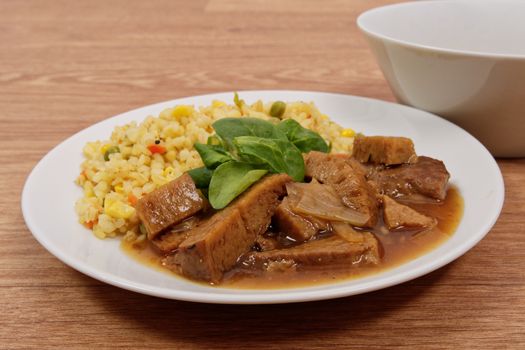 Tempeh with tomato sauce and millets on a wooden table