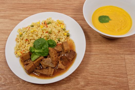 Tempeh with tomato sauce and millets on a wooden table