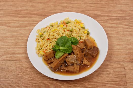 Tempeh with tomato sauce and millets on a wooden table